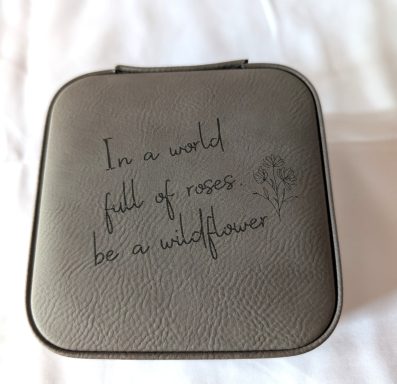 Gray 4" travel jewelry box with velvet interior complete with ring holders and separate compartments for earrings or necklaces.